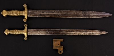 pair of antique brass - plated daggers on a black background