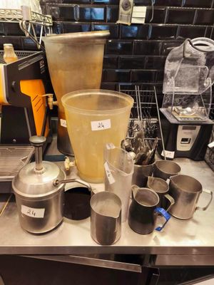 a counter with a blender, a blender, cups, and other items on it