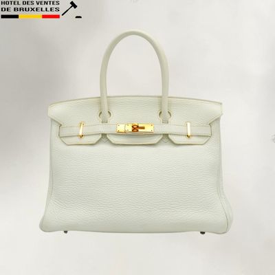 a white leather handbag with gold hardware on a white background