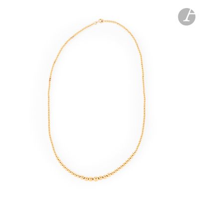 a gold necklace with a beaded chain on a white background