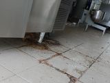 a dirty floor in a kitchen with a refrigerator in the background