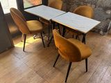 tables and chairs in a room with a brick wall and a window