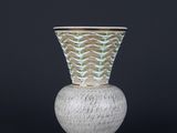 un vase blanc et vert posé sur un socle blanc