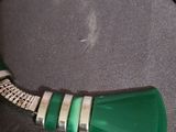 silver and green necklace on a black surface with a silver chain