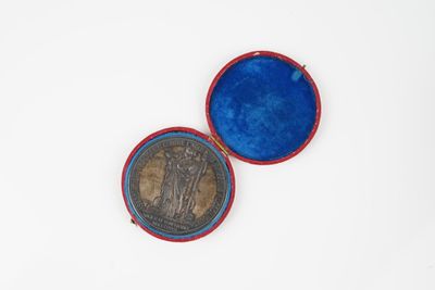une vieille pièce de monnaie dans un étui bleu posé sur une surface blanche