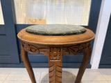 une vieille table en bois avec un plateau en marbre, posée sur un sol carrelé