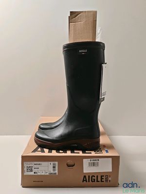 black rubber boots on top of a cardboard box on a white surface