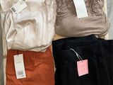 trois paires de pantalons et un t-shirt posés sur une caisse en bois