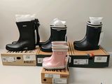 three pairs of pink and black rain boots sitting on top of boxes