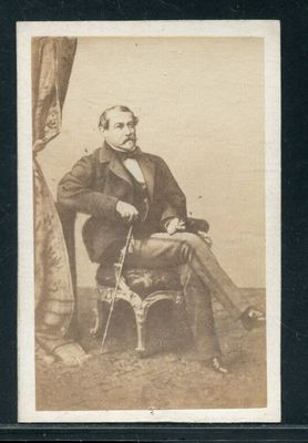 portrait d'un homme assis sur une chaise, une canne à la main