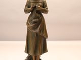 statue en bronze représentant une femme tenant un bébé dans ses bras, posée sur un socle en bois