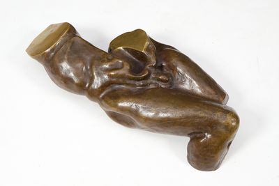sculpture en bronze représentant un bébé tenant un biberon, posée sur une surface blanche