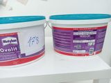 two buckets of paint sitting on a shelf