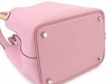 the small pink bag is sitting on a white surface