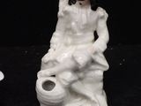 two figurines of people sitting on a black surface
