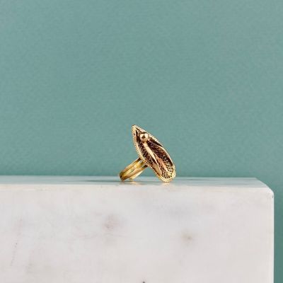 un gros plan d'une bague en or posée sur un bloc de marbre