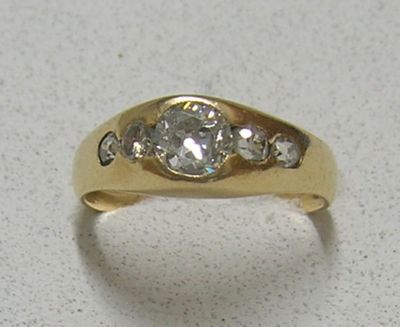 une bague en or sertie d'un diamant, posée sur une table