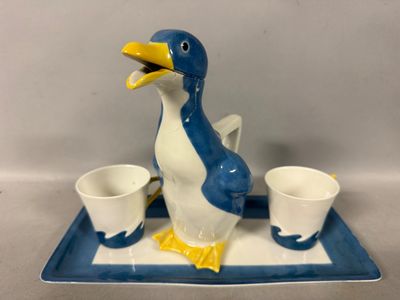 a blue and white penguin figurine with two cups on a tray