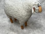 a stuffed sheep that is standing on a cement floor