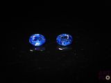 a pair of blue glass beads sitting on top of a black surface