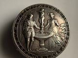 an old silver coin with a picture of a man and a woman at a fountain