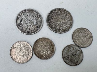 six types différents de pièces d'argent posées sur une surface blanche