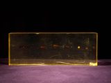 a clear box with a yellow object in it on a purple surface
