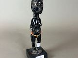 a small statue of a woman in a black dress stands on a black base