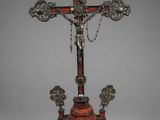 a silver and red cross on a stand with a chain around it
