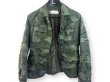 une veste de camouflage verte suspendue à un cintre sur un mur blanc
