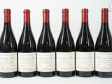 six bouteilles de vin sont alignées sur une surface blanche