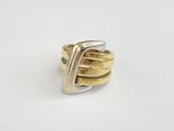 gros plan d'une bague en or et en argent sur une surface blanche