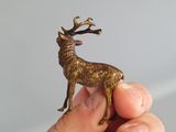 a hand holding a small bronze deer figurine in it ' s left hand