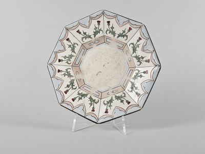 une image représentant une assiette décorative posée sur un socle, sur fond blanc