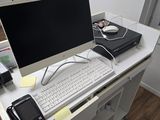 a desk with a computer, phone, and other items on it