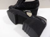 pair of black platform shoes with buckles on a white surface