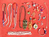 de nombreux colliers et bracelets de toutes sortes disposés sur un fond rouge