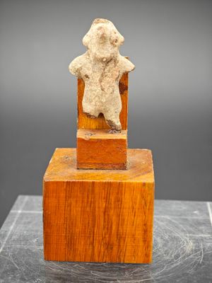 une photo d'une sculpture représentant un ours en peluche assis sur un bloc de bois