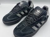 Les baskets adidas sont noires et grises, avec une bande argentée.