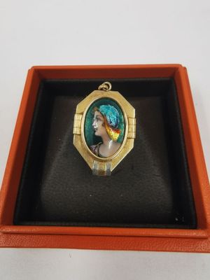 un gros plan sur une bague dans un écrin, avec la photo d'une femme