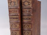 two old books sitting on top of each other on a white surface