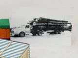 a black and white photo of a truck and a pile of logs