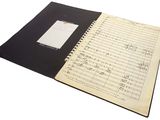 an open notebook with music notes and a notepad on it