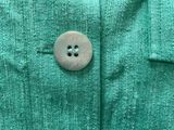 a button on a green shirt that is being worn