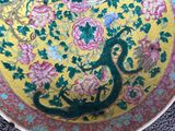 a yellow plate with a dragon and flowers on it