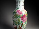 un vase avec des fleurs peintes dessus, posé sur une table
