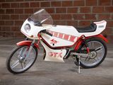 a red and white motorcycle parked in front of a brick wall