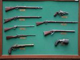 a lot of guns on display in a wooden frame