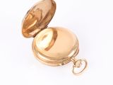 a gold pocket watch sitting on a white surface