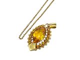 a close up of a necklace with a yellow stone on a chain